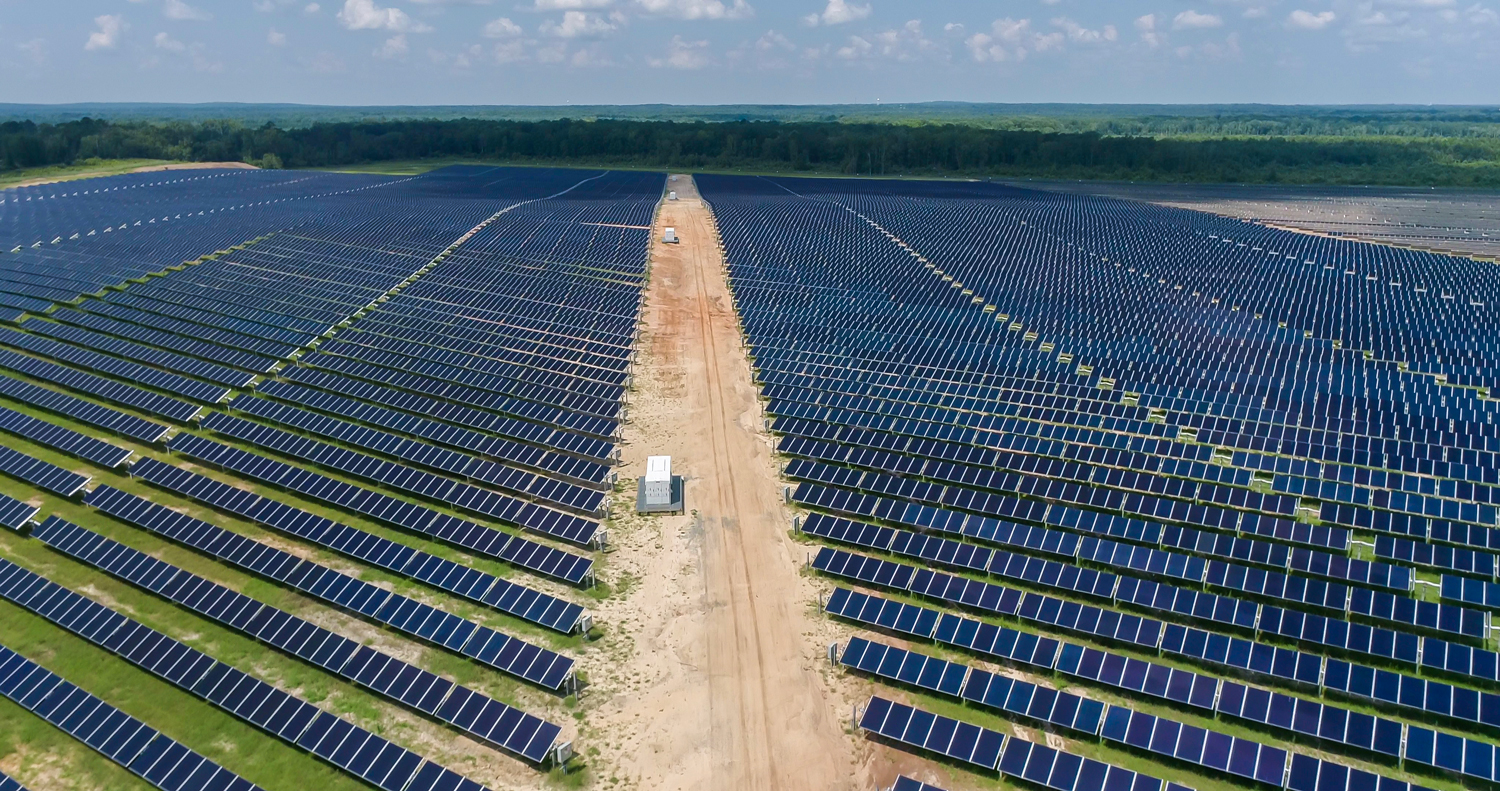 Central access road cutting through rows of solar panels at GA Solar 4 site.