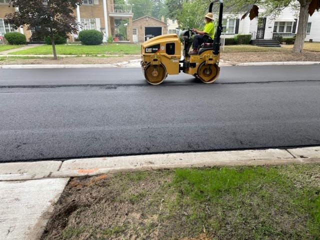 Asphalt roller smoothing freshly laid pavement on Reynolds Street in Muskegon Heights.