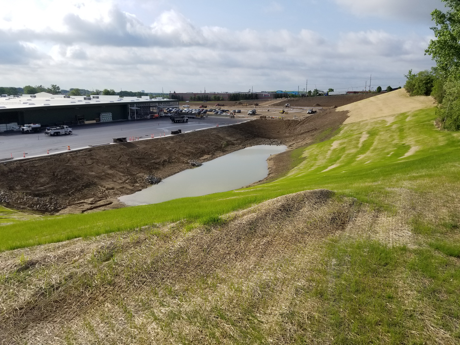 View of a detention pond and parking area under construction at the Menards Commercial Development site in Orion Township, Michigan.