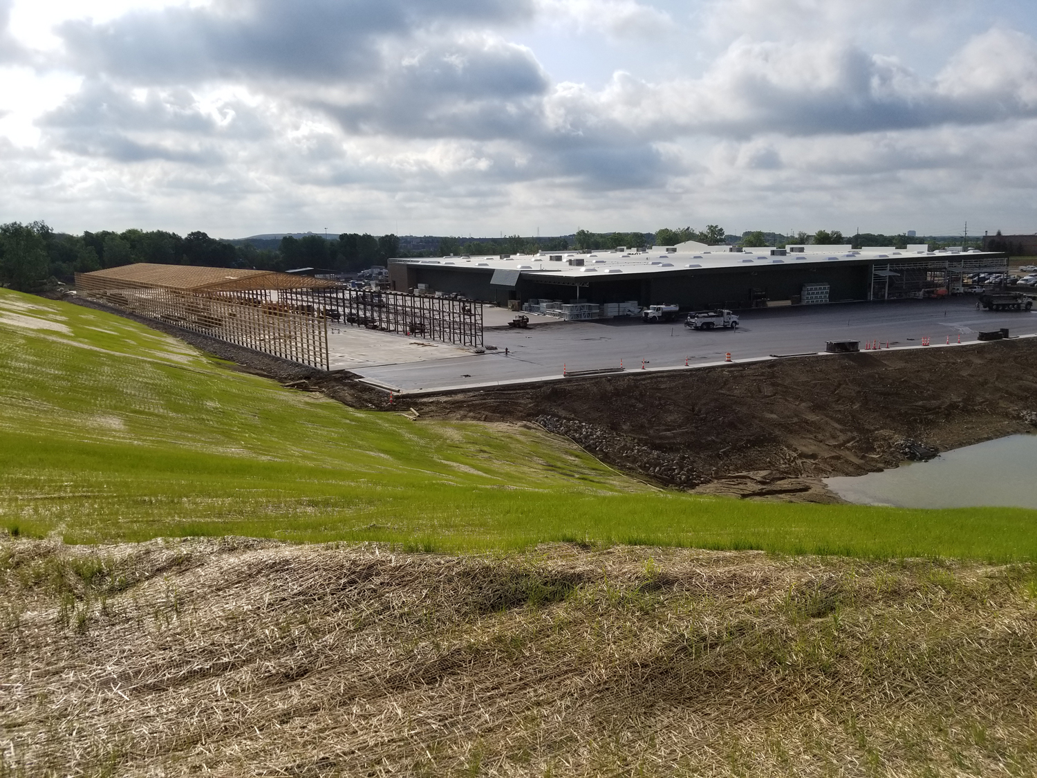 Graded hillside overlooking the construction site for Menards Commercial Development with visible structural framing and detention pond.