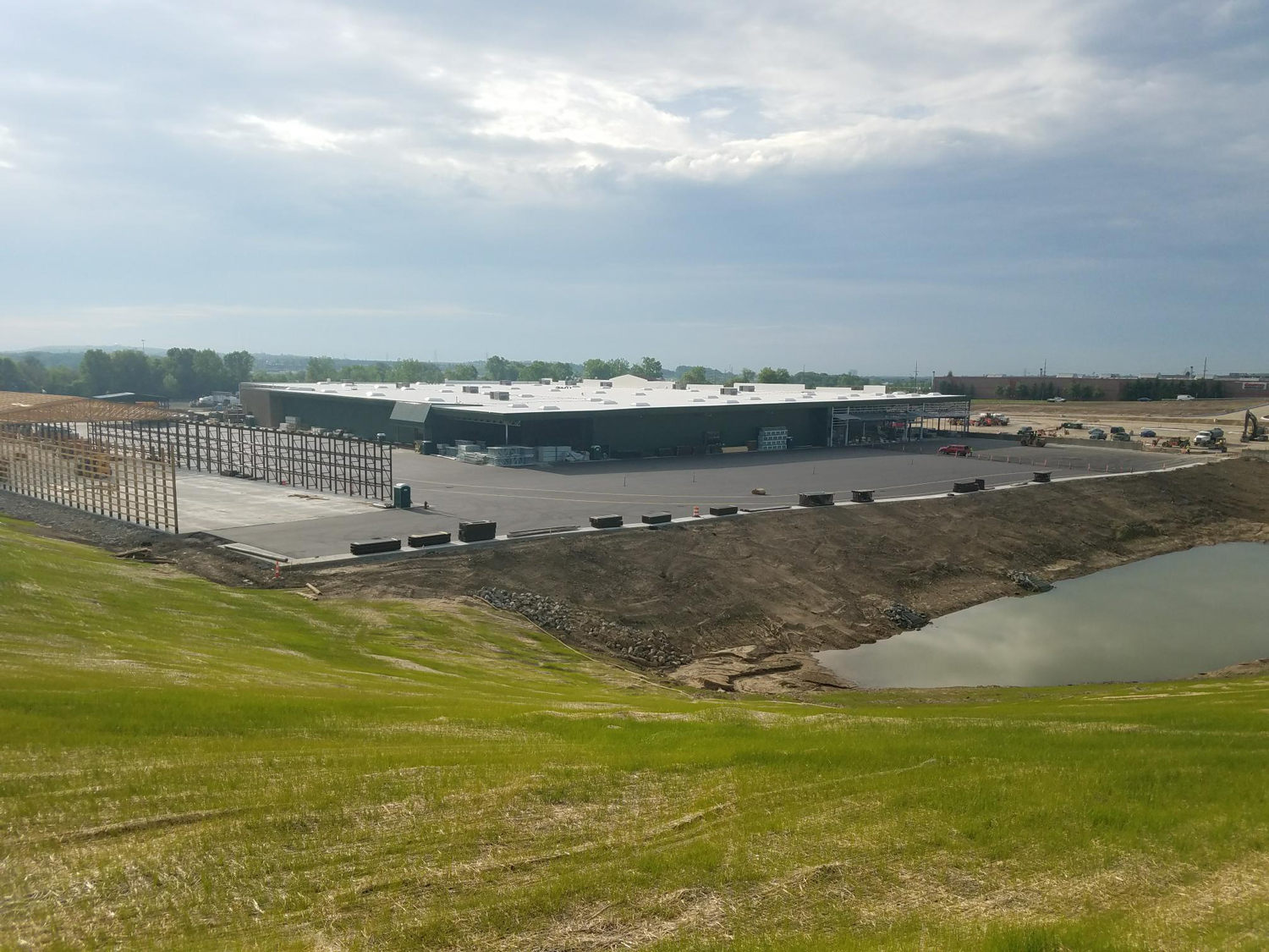 Graded slope adjacent to the Menards construction site, showing erosion control and newly seeded grass areas.