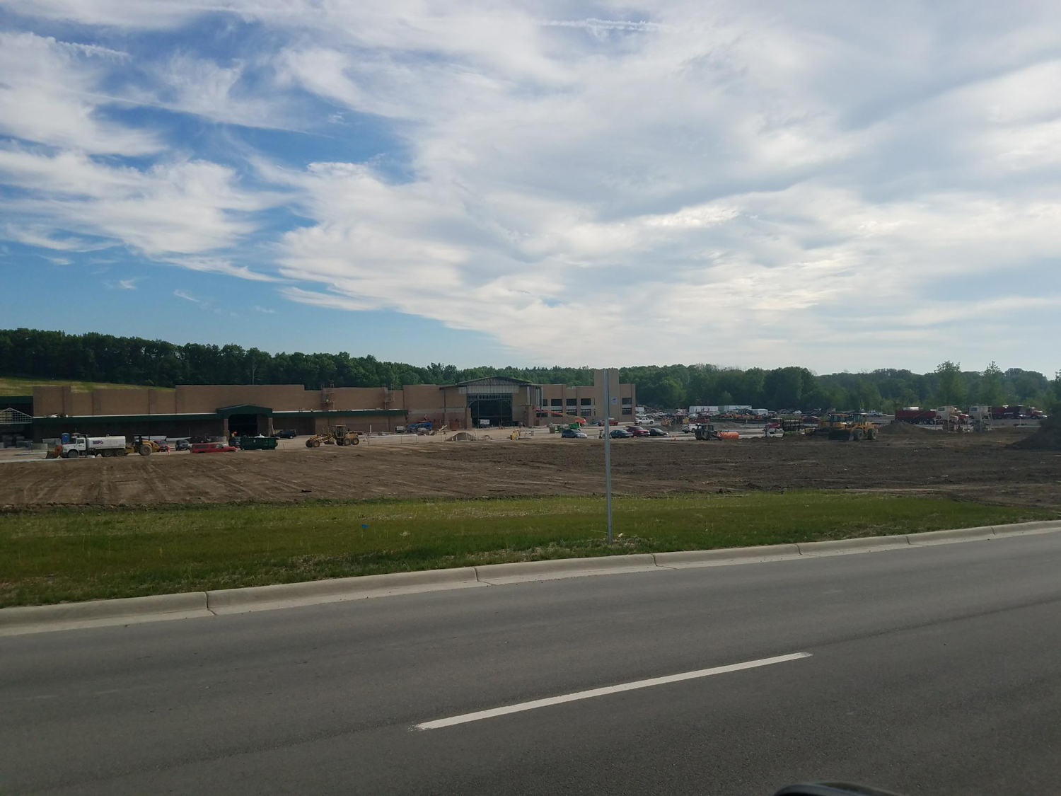 View of the hillside next to the Menards site with grass restoration and construction activities in the background.