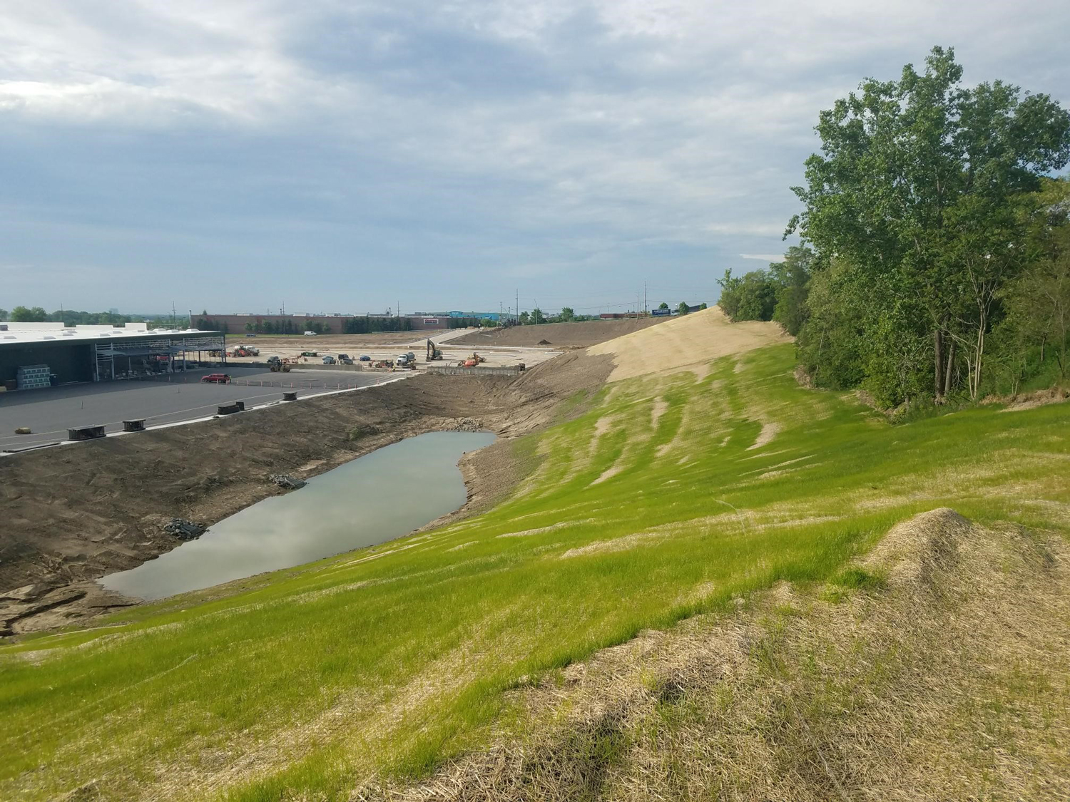 Detention pond and graded areas with visible progress on the Menards Commercial Development site.