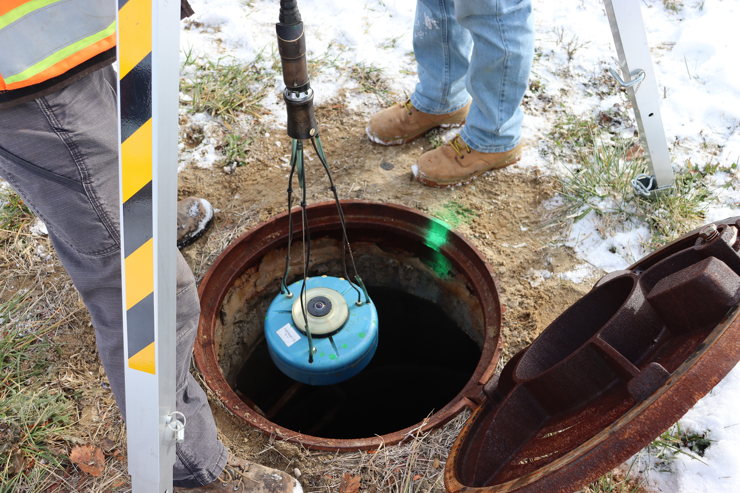 Manhole scanning equipment being lowered into a sewer manhole for underground infrastructure inspection